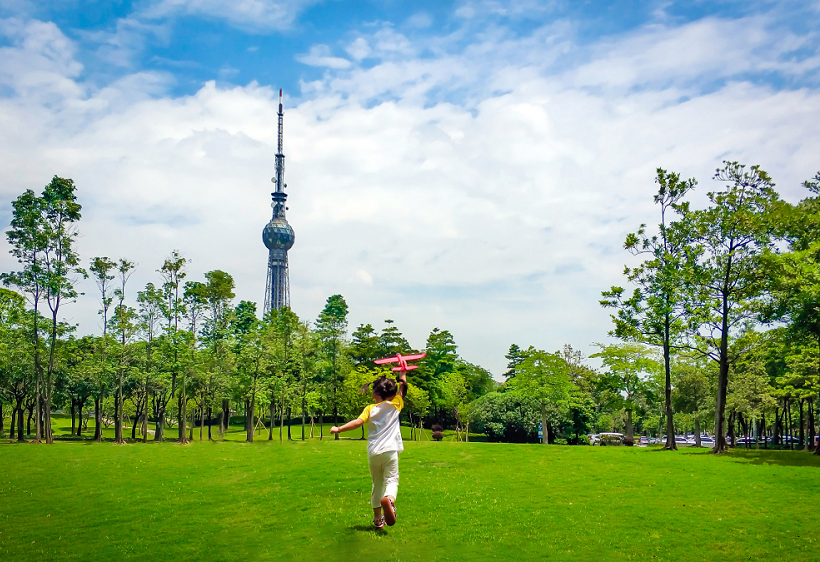 广东省佛山市禅城区文华公园，蓝天白云绿树，小孩尽情玩耍，放飞童梦。（摄影：李捷婷）